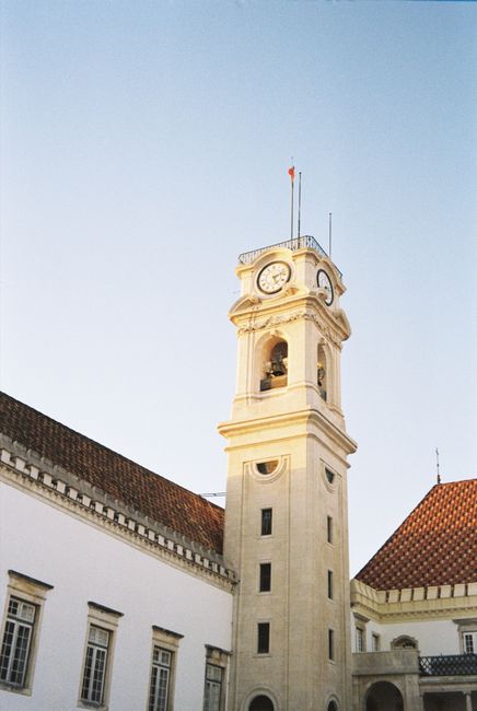 A low-angle view of the historic clock tower at the University of Coimbra, Portugal.