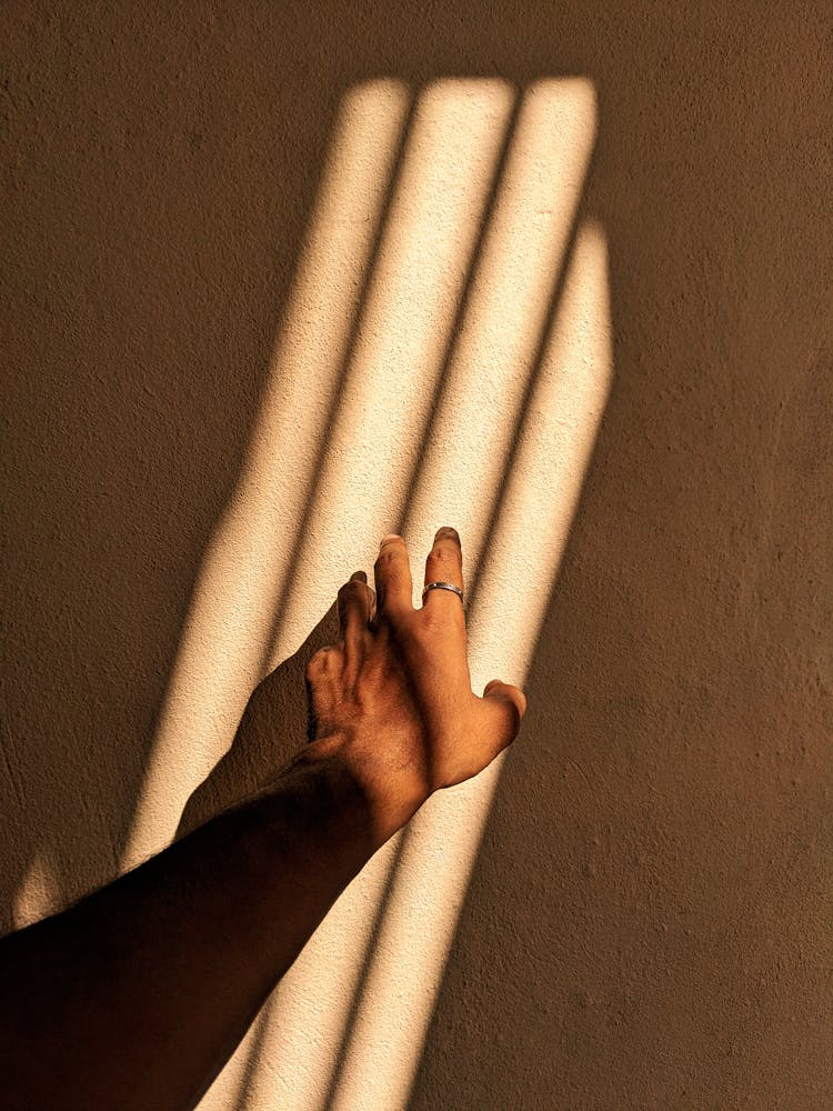 Close-up Of Hand Touching Light On Wall