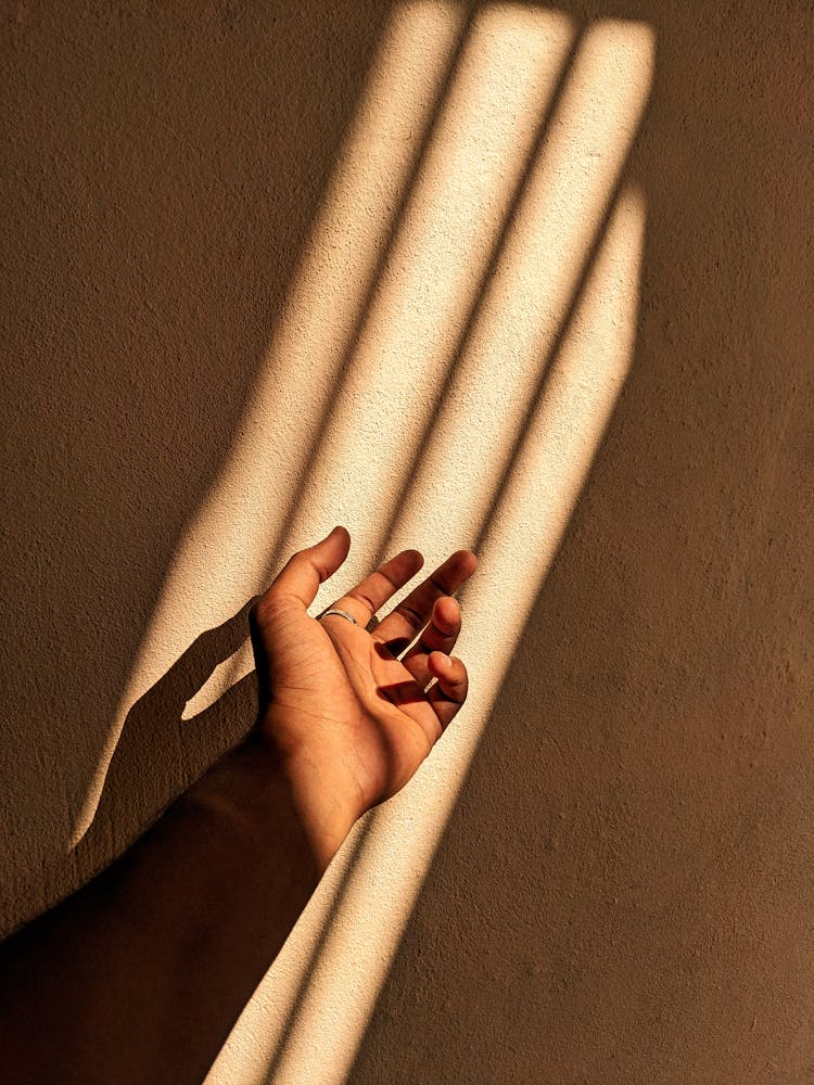 Close-up Of Hand In Light On Wall Background