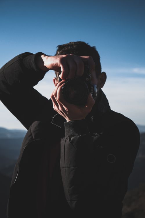 Free Outdoor silhouette of a photographer capturing a scenic view with a camera in hand. Stock Photo