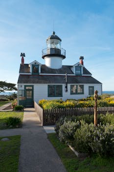 Charming lighthouse and cottage in Pacific Grove, California, surrounded by vibrant garden.