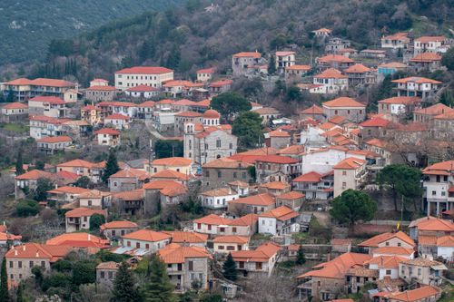 Free Picturesque aerial view of Andritsaina, Greece with traditional red-roofed houses nestled in a hilly landscape. Stock Photo