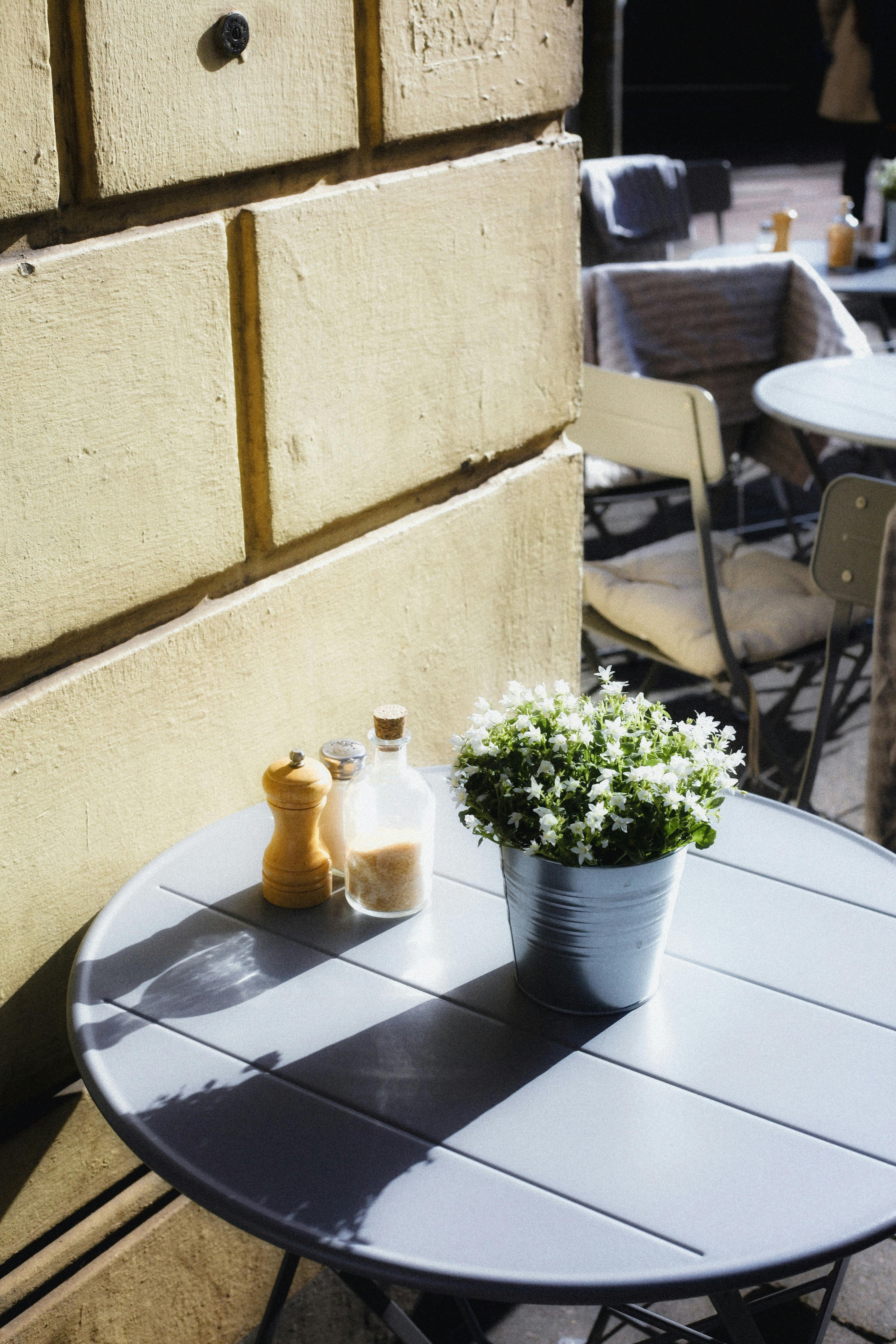 Inviting outdoor café scene featuring a round table with flowers, salt, and pepper shakers under warm sunlight.