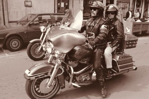 Free Two motorcyclists with leather jackets ride a classic bike through city streets. Stock Photo