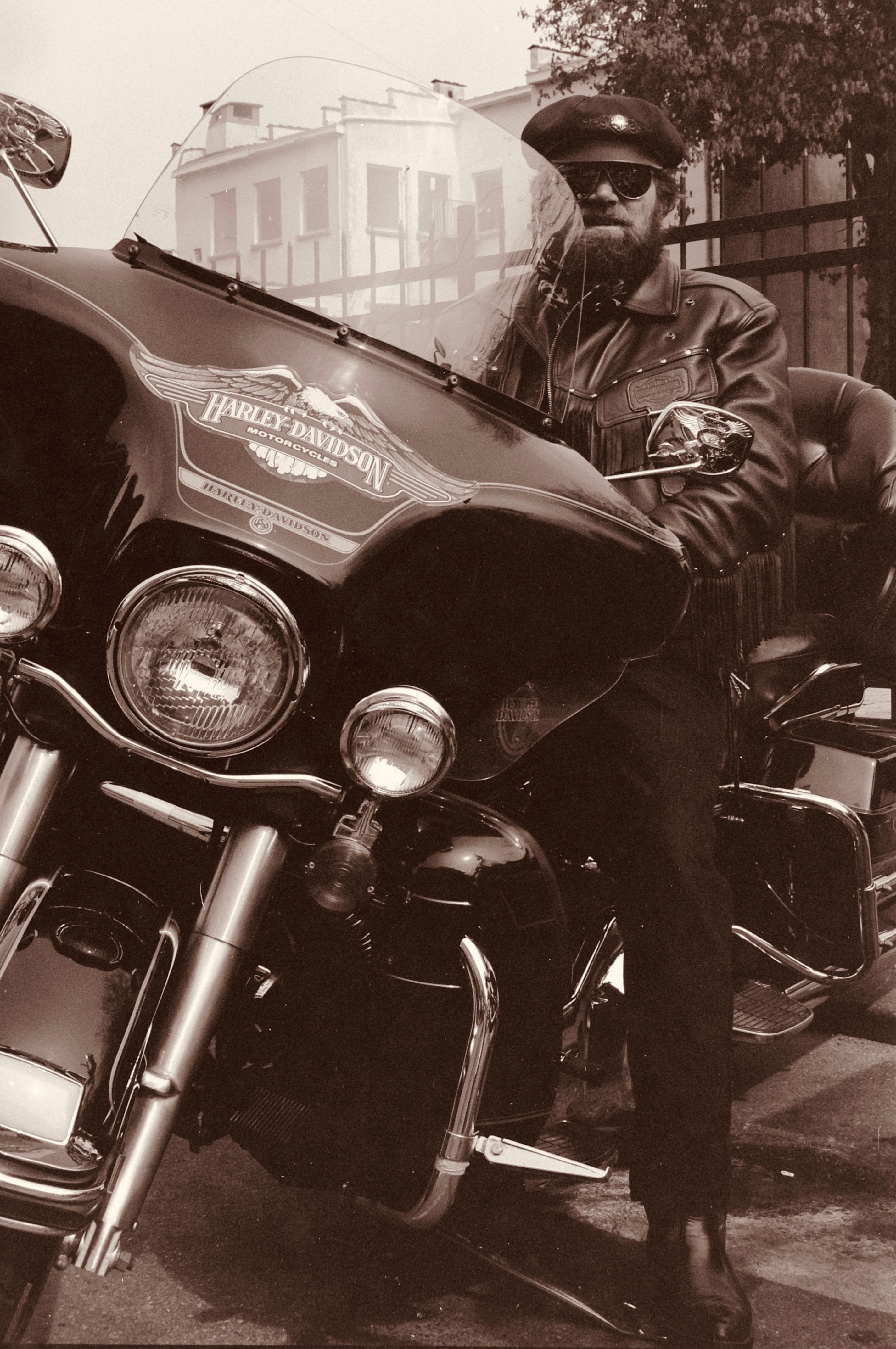 Motorcyclist in leather jacket sitting on a Harley-Davidson, sepia tone.