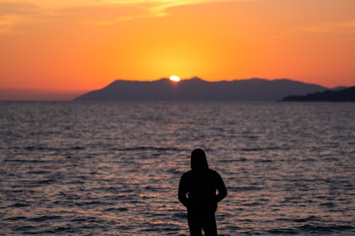 Silhouette of a Lone Person Looking at the Sea at Sunset