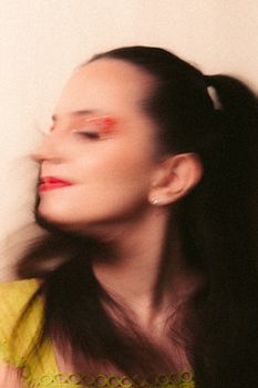 Artistic studio shot of a woman in motion blur with bright makeup and blurred features.