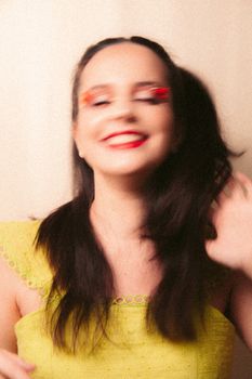 Vibrant blurred portrait of a smiling woman with colorful eye makeup and red lips.