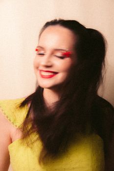 Artistic portrait of a smiling young woman with creative makeup and flowing hair.
