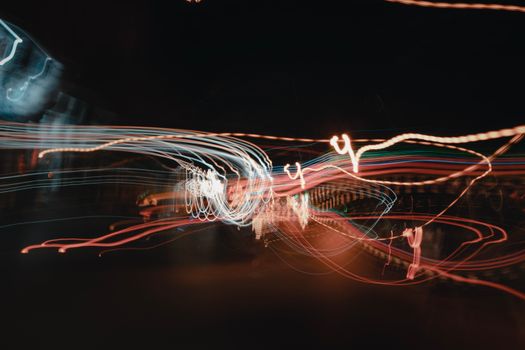Abstract long exposure photo capturing colorful light trails against a dark background.