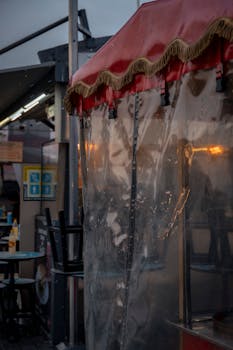 A vibrant evening street market with an empty stall covered in plastic under a roof.