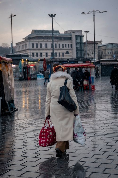 Free A woman carries bags while walking through a rainy city square in Istanbul, Turkey. Stock Photo