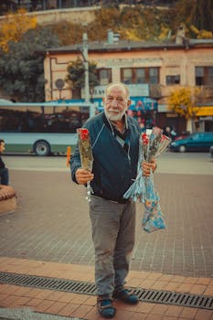 An elderly man sells roses on a bustling street in Bursa, Turkey. Warm autumn tones highlight the scene.