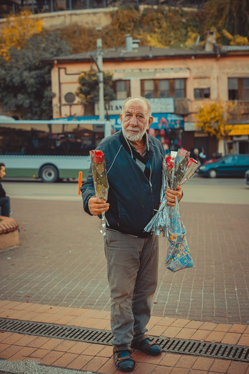 Free An elderly man sells roses on a bustling street in Bursa, Turkey. Warm autumn tones highlight the scene. Stock Photo