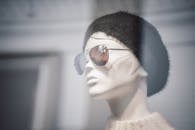 商店橱窗里，一个时髦的人体模特戴着无檐帽和太阳镜，展示着现代时尚