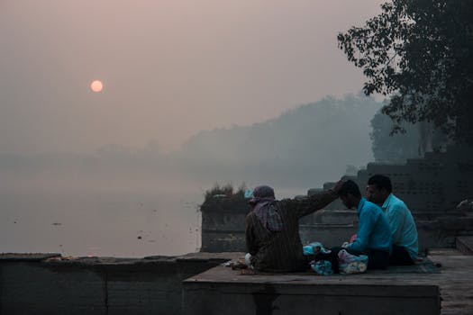 黎明时分，三名男子在印度薄雾缭绕的河岸旁平静地进行仪式