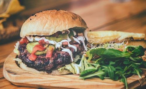 бесплатная Гамбургер на коричневой деревянной разделочной доске Стоковое фото