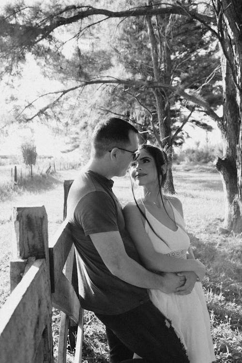 Black and White Photo of a Couple Standing by the Fence 