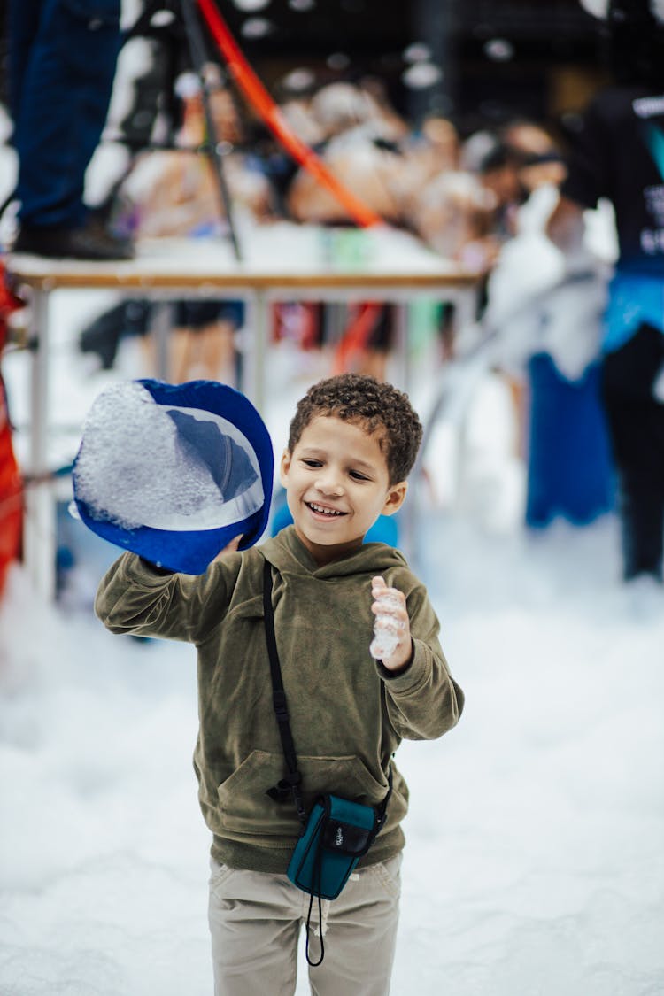 Little Boy Holding Hat Full Of Fluffy Foam