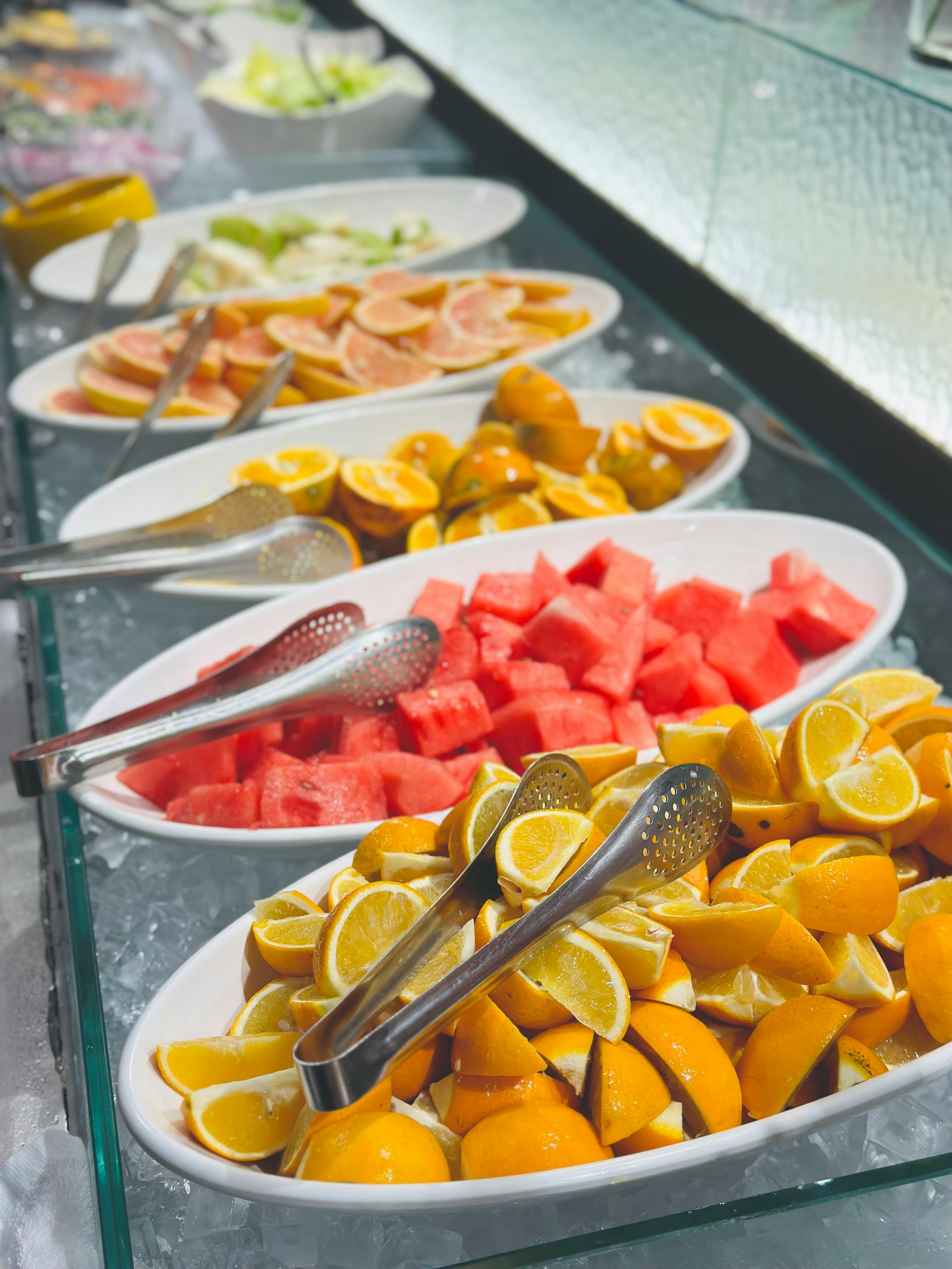 Vibrant fruit buffet display showcasing citruses and melons in a restaurant setting.