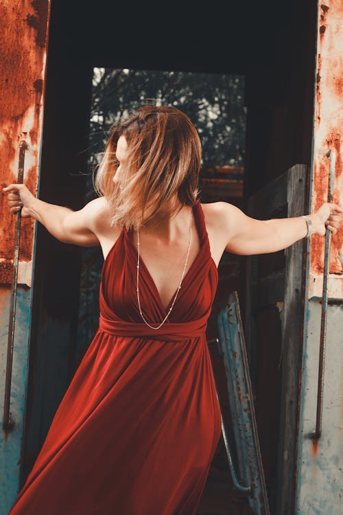 Female Model Wearing a Red Dress Gripping Doorway Handles