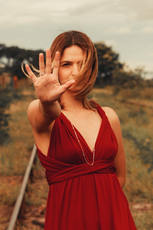 Female Model Wearing a Red Dress Reaching toward the Camera