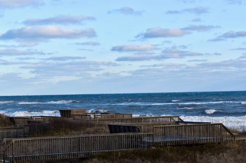 Free Beautiful coastal scene featuring a wooden boardwalk overlooking the ocean's waves. Stock Photo