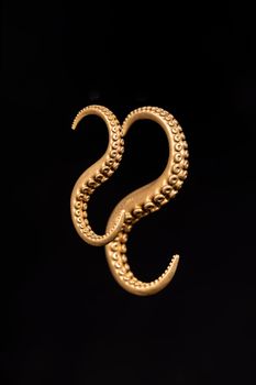 Close-up of copper octopus tentacle earrings on a dark background, showcasing intricate metalwork.