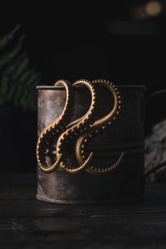 Close-up of copper octopus tentacles on a rustic metal can, evoking a handmade art piece feel.