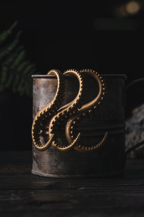 Free Close-up of copper octopus tentacles on a rustic metal can, evoking a handmade art piece feel. Stock Photo