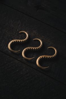 Stylish gold earrings in a unique octopus tentacle design on a dark wooden background.