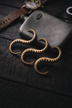Stylish arrangement of golden hangers and a hip flask on a rustic wooden table.