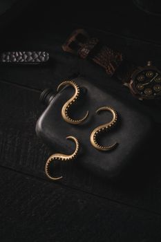 A steampunk-themed arrangement with a watch and octopus hooks on a flask.