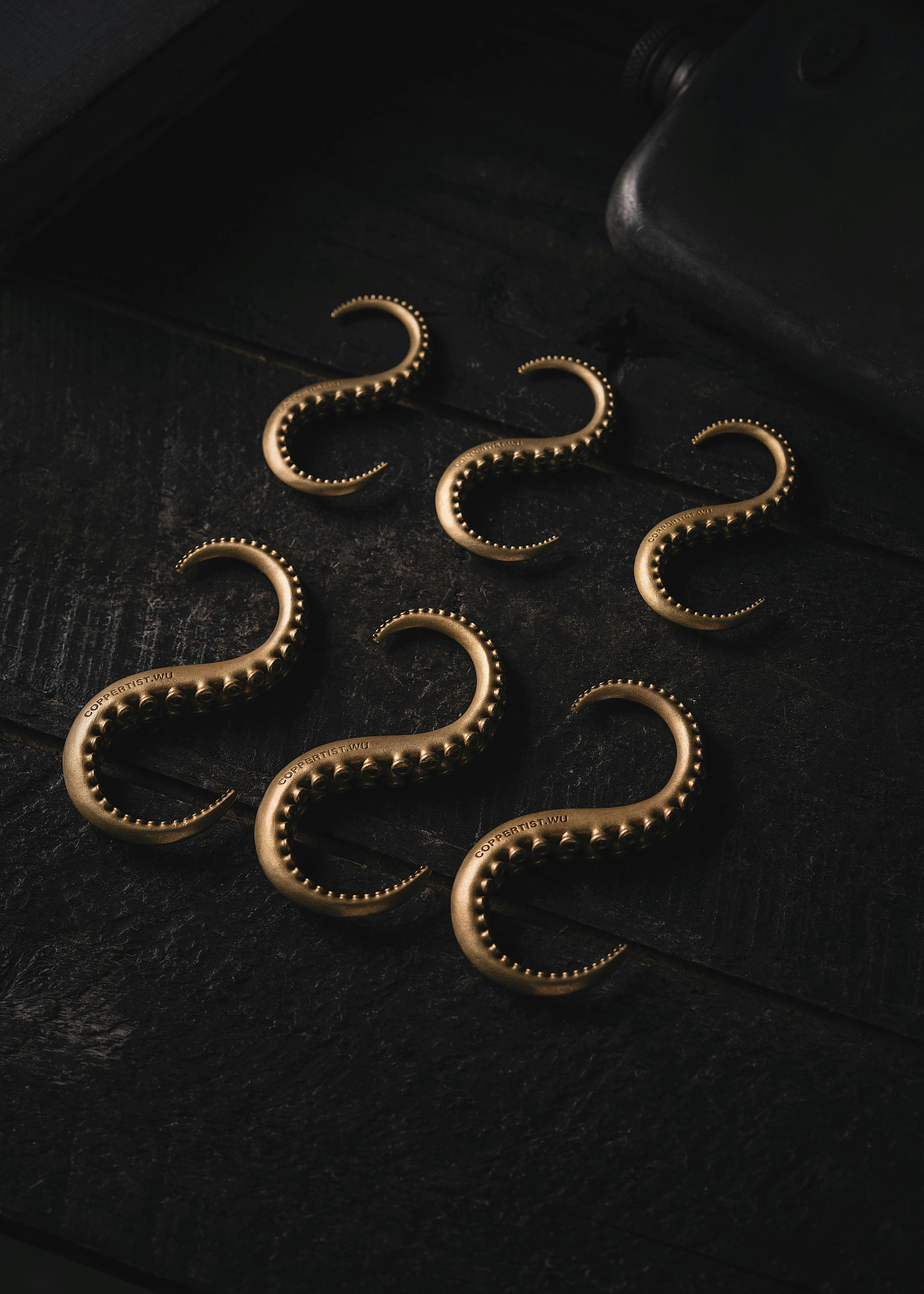 Close-up of Brass Octopus Tentacle Hooks on Black Background