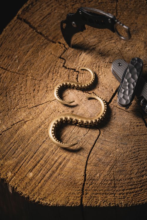 Free Artistic brass octopus tentacle hooks and tools on rustic wooden background. Stock Photo