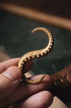 Artistic brass tentacle hook held in hand, showcasing intricate craftsmanship and vintage appeal.