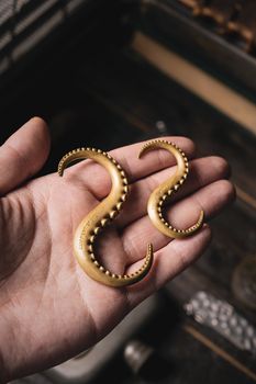 Close-up of ornate brass octopus tentacle hooks held in hand, capturing vintage charm.