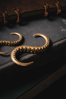 Bronze octopus tentacle hooks on an aged leather book evoke a sense of nostalgia and mystery.