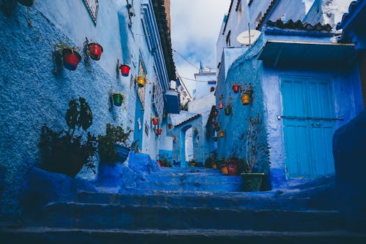Colorful pots line the blue-washed walls of a narrow alley in Chefchaouen, Morocco.