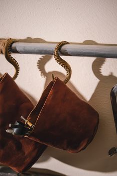 Close-up of a vintage leather bag on decorative octopus tentacle hooks.