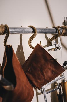 Close-up of vintage leather tool bags hanging on ornate hooks, showcasing intricate details.