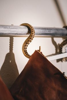 Elegant octopus tentacle hanger holding a stylish brown coat under warm lighting.