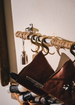 Close-up of vintage leather tool bags hanging on ornate, brass octopus tentacle hooks against a wall.