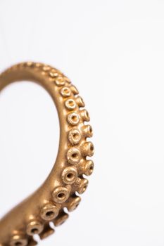 Close-up of a gold octopus tentacle-shaped sculpture with smooth background.