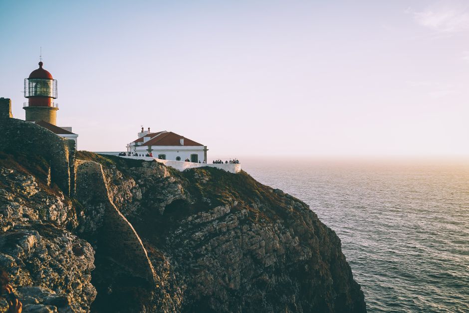 Dramatic cliffside view of a lighthouse at sunset in Santarém, Portugal.