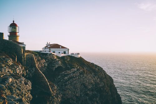 Free Dramatic cliffside view of a lighthouse at sunset in Santarém, Portugal. Stock Photo