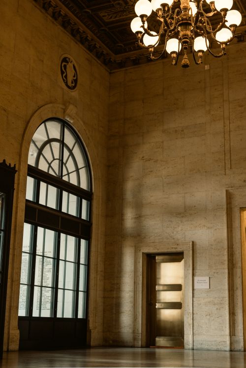 Free Classic interior featuring a glowing chandelier and arched window, captured in warm tones. Stock Photo