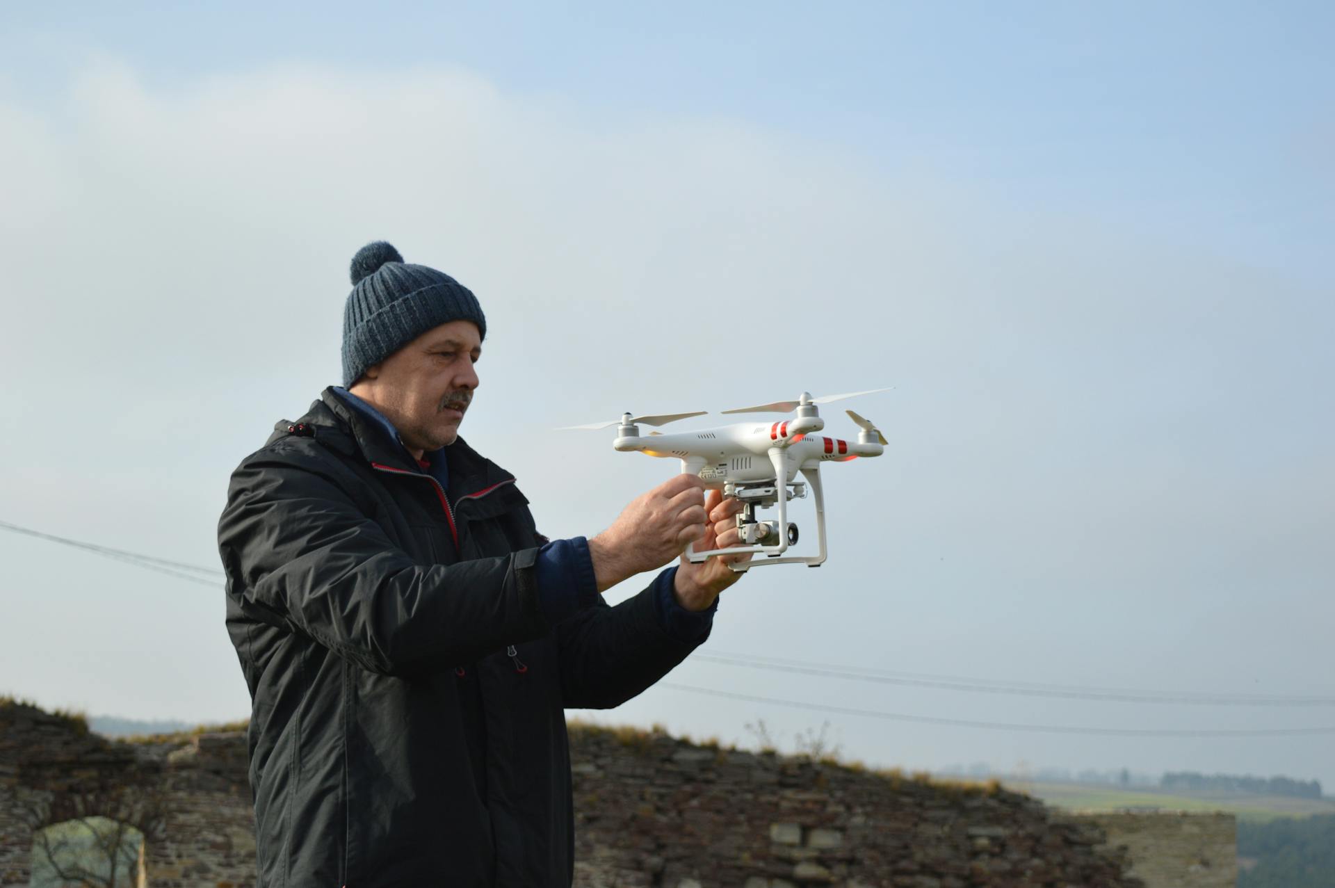 A man prepares a quadcopter drone for flight outdoors on a clear day.