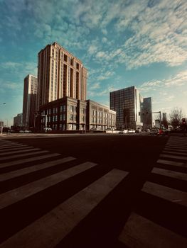 A striking city intersection showcasing towering buildings and a cloudy sky, featuring a zebra crossing.