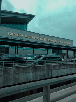 View of vehicles outside Ninoy Aquino International Airport on a cloudy day.
